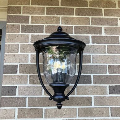 Black outdoor wall-mounted coach lantern on brick wall